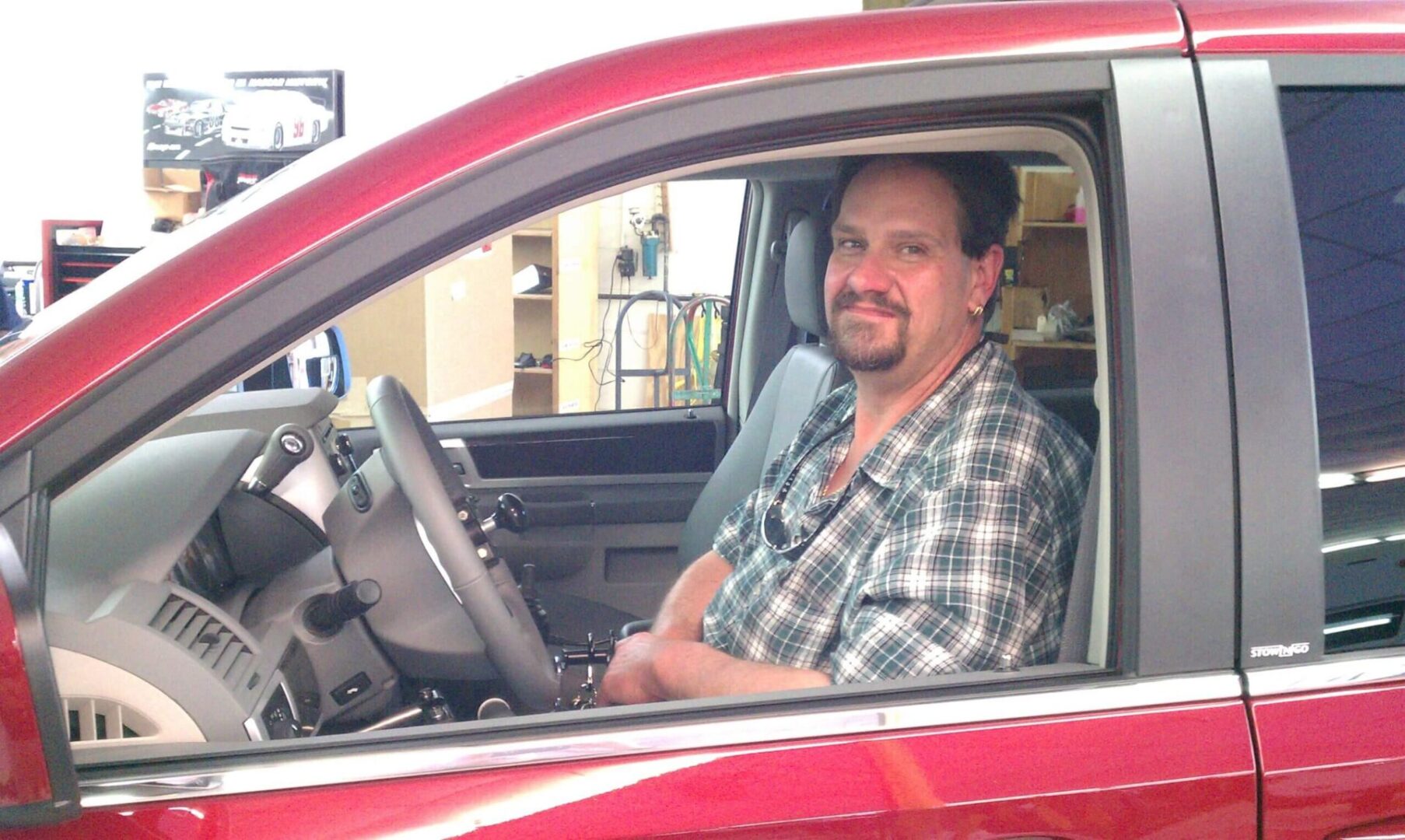 A smiling man inside a red car