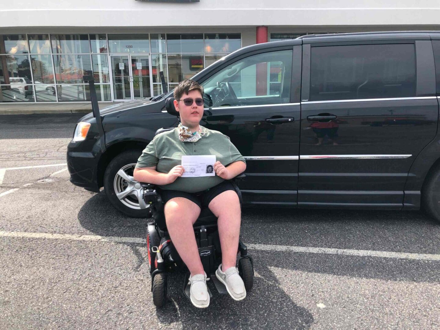 A person sitting in a wheelchair and holding a sign